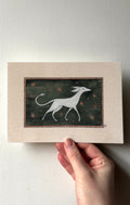 'The Spirit' print held in a hand: a white hound-like creature walking on a dark green starry background