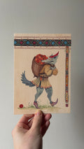 "The Gatherer" print held in a hand: Beaste Morble, a wolf-like creature carrying a basket of red apples