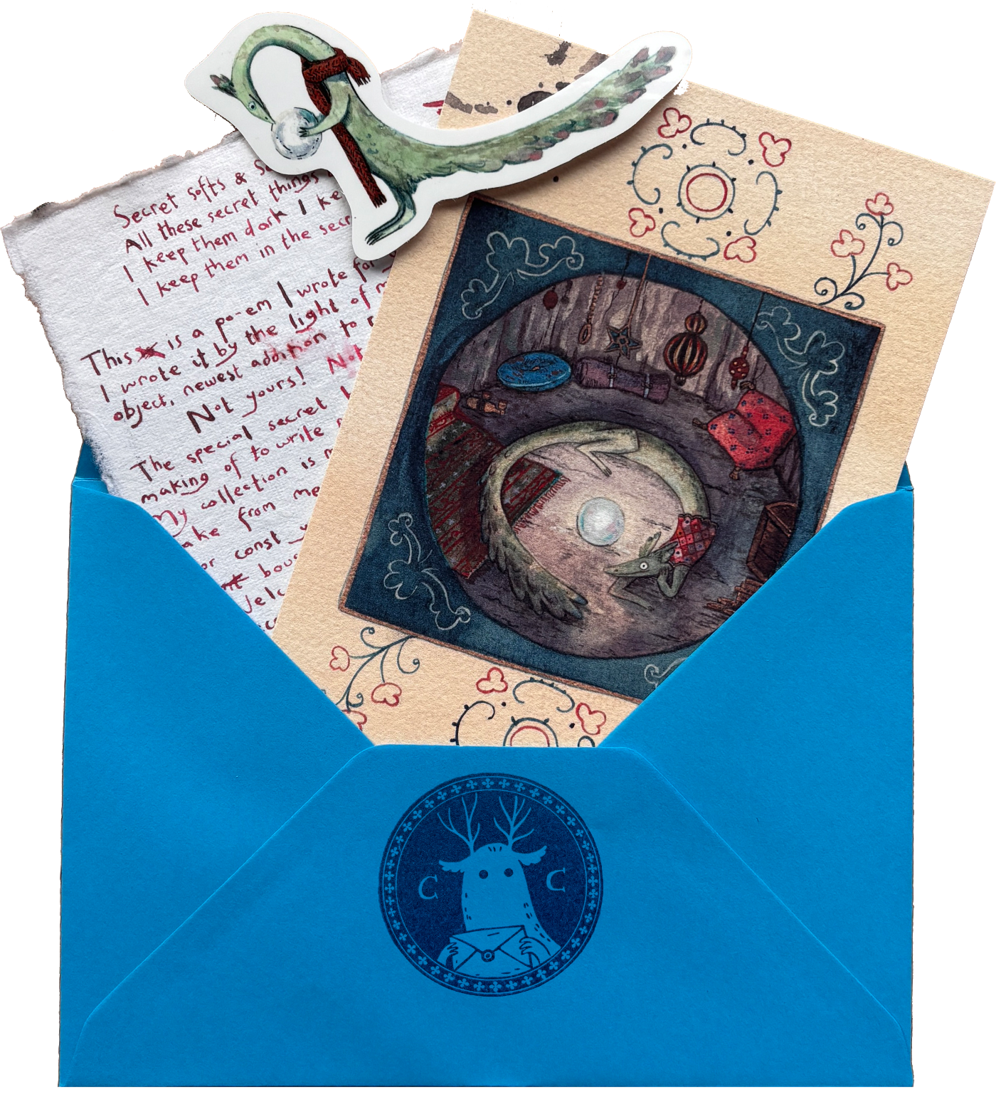 A styled flat-lay of a blue envelope with a dark blue deer logo, partially opened to reveal a whimsical illustrated card and handwritten notes.