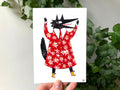 "Wolf in a Fancy Coat" print held in a hand: a black wolf in a red flowered coat with its arms raised