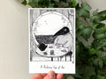 "Relaxing Cup of Tea" print held in a hand: Birdface at a table with a teapot by a round window over the sea