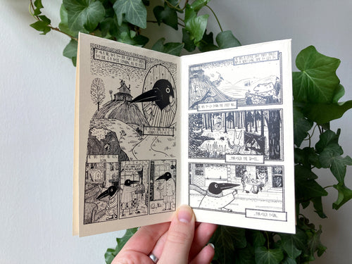 The zine held open in front of ivy: black and white illustrated pages of Birdface's daily life