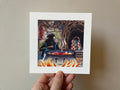 "Good Soup" print held in a hand: a creature stirring a pot of red soup over a fire in an underground house
