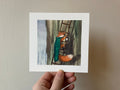 "The Climb" print held in a hand: a fox in a green cloak climbing a ladder