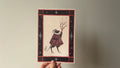 "The Lightbearer" print held in a hand: a cloaked creature carrying a branch of lit candles, in a dark starry border